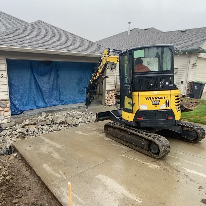 Excavator placing stones in trailer of Tiger Landscaping